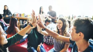 Diverse students giving high five to team